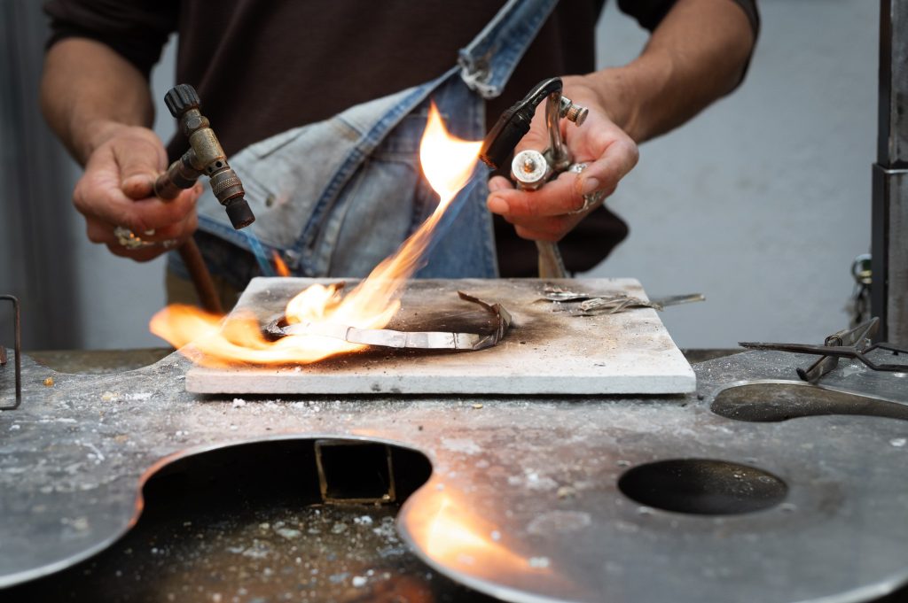 Artisan joaillier FUSYOM façonnant une création unique à la flamme dans son atelier sur l'île d'Oléron.